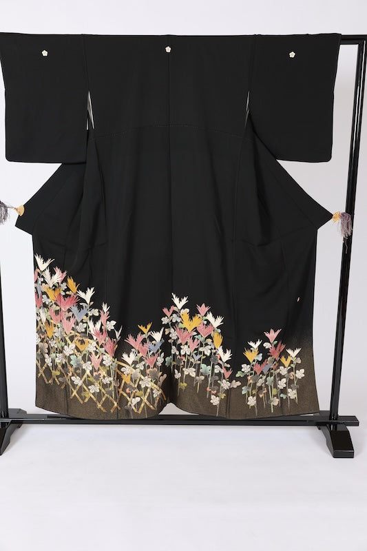 Black formal kimono used (Kurotomesode) with plum blossom design, gold, gray, ochre, coral, shades of green, gold thread embroidery, bamboo fence, and flowers. Artist-made. L46