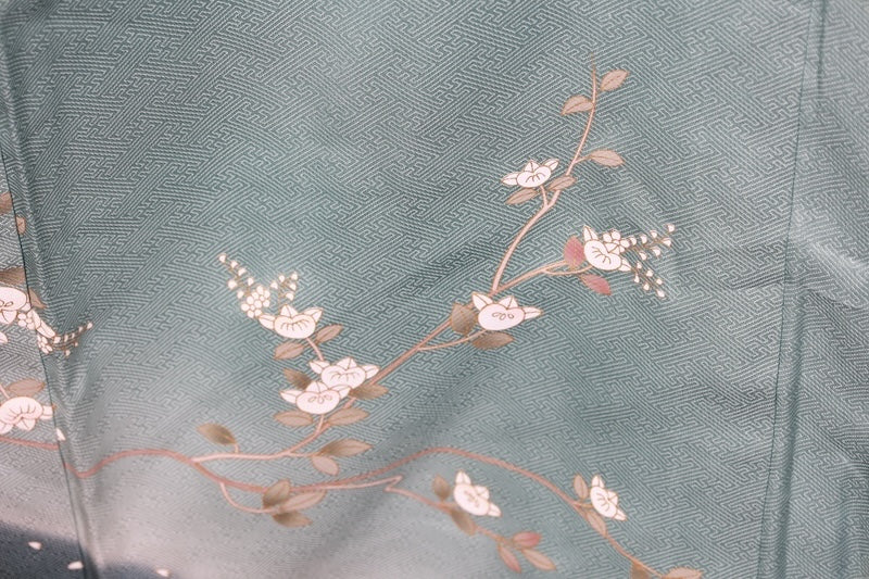 New, unused formal kimono (houmongi) in light blue, gold, brown, green, and white, with a continuous woven pattern of tachibana (mandarin orange) and children's motifs. (R90)