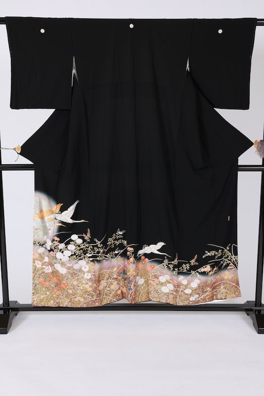 Black formal kimono (Kurotomesode) with five crests and a sword-shaped wood sorrel design. Colors: indigo, green, coral, gold, silver, white, purple. Features flowers, cranes, and gold embroidery. J10