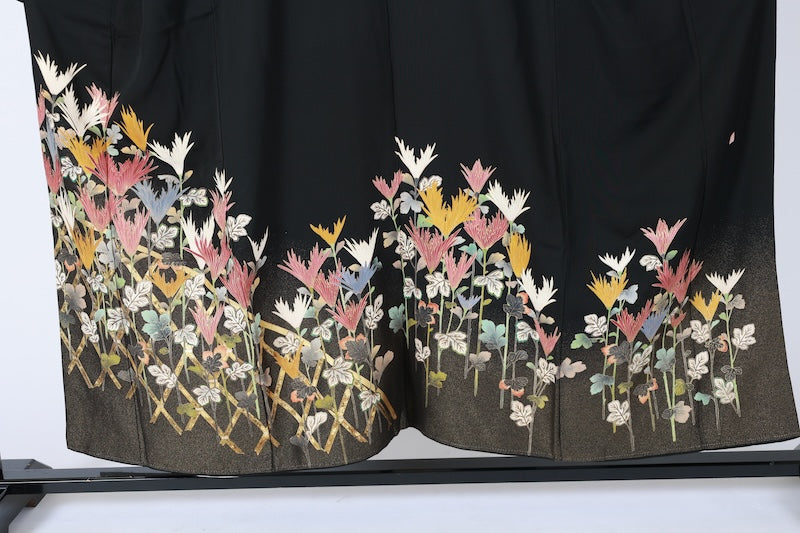Black formal kimono used (Kurotomesode) with plum blossom design, gold, gray, ochre, coral, shades of green, gold thread embroidery, bamboo fence, and flowers. Artist-made. L46